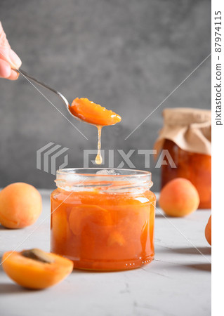 Homemade apricot jam in spoon in woman's hand. 87974115