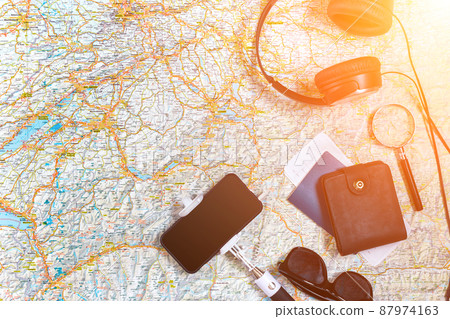 Accessories for travel. Passport, headphones, smart phone and travel map. Top view. Sun flare 87974163