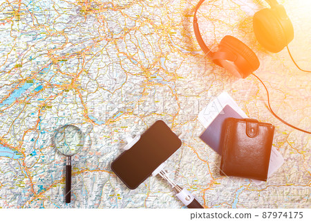 Accessories for travel. Passport, headphones, smart phone and travel map. Top view. Sun flare Accessories for travel. Passport, headphones, smart phone and travel map. Top view. Sun flare 87974175
