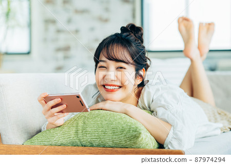 年輕女子在客廳看智慧型手機 年輕女子在客廳看智慧型手機 87974294
