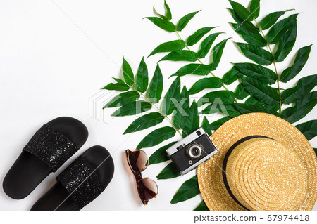 Straw hat with green leaves and old camera on white background, Summer background. Top view 87974418