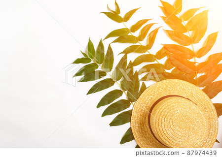Green leaf branches and straw haton white background. flat lay, top view. Sun Flare 87974439