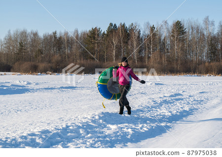 Fun Young woman snow tube in winter park. Leisure on nature, snow slide skiing. Concept of interactive entertainment. Fun Young woman snow tube in winter park. Leisure on nature, snow slide skiing. Concept of interactive entertainment. 87975038