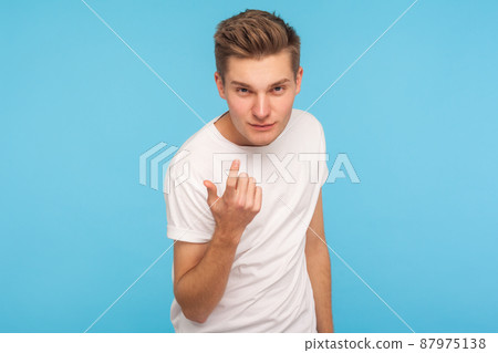 Come to me. Portrait of handsome man in casual white t-shirt making beckoning gesture and looking at camera with alluring eyes, flirting asking for date. indoor studio shot isolated on blue background Come to me. Portrait of handsome man in casual white t-shirt making beckoning gesture and looking at camera with alluring eyes, flirting asking for date. indoor studio shot isolated on blue background 87975138