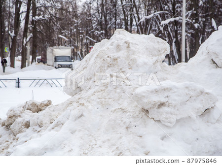 A high large snowdrift by the road against the backdrop of a city street A high large snowdrift by the road against the backdrop of a city street 87975846