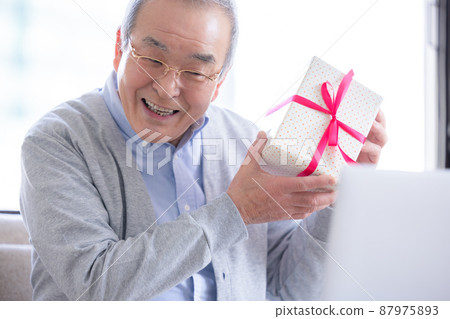 視頻通話：一位老人打開了寄給他的禮物，他的家人在線連接。 87975893