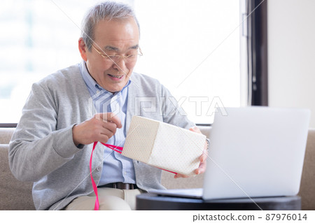 視頻通話：一位老人打開了寄給他的禮物，他的家人在線連接。 87976014