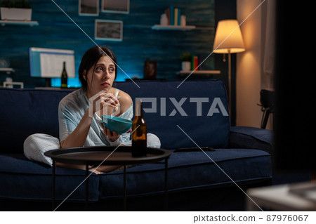 Sad lonely woman with chronic depression watching TV show on screen, feeling desperate and dealing with mental health issues. Depressed anxious adult looking at movie on television. Sad lonely woman with chronic depression watching TV show on screen, feeling desperate and dealing with mental health issues. Depressed anxious adult looking at movie on television. 87976067