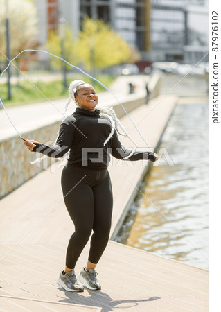 Afro-american plus size woman doing workout exercises session outdoor Afro-american plus size woman doing workout exercises session outdoor 87976102