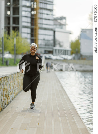 Afro-american plus size woman jogging outdoor Afro-american plus size woman jogging outdoor 87976106