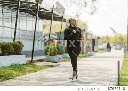 Afro-american plus size woman jogging outdoor Afro-american plus size woman jogging outdoor 87976148