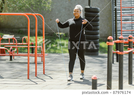 Afro-american plus size woman doing workout exercises session outdoor Afro-american plus size woman doing workout exercises session outdoor 87976174