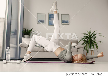 Girl in a sports uniform make yoga at home Girl in a sports uniform make yoga at home 87976236