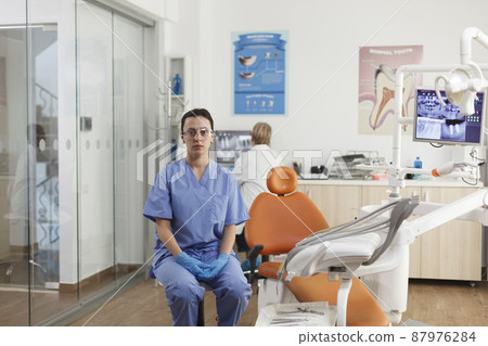 Portrait of stomatologist assistant working at stomatological treatment in dentistry medical office during dentistry examination. Medical team analyzing teeth radiography. Medicine services 87976284