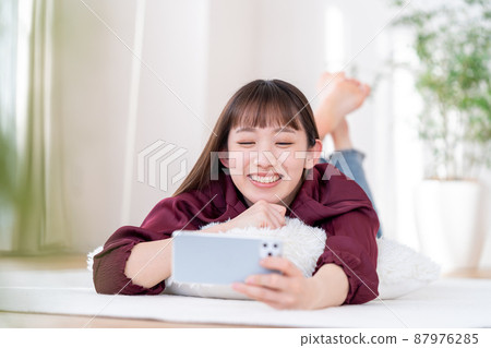A young woman operating a smartphone 87976285