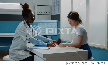 Medical specialist giving bottle of pills and checkup paper to patient for healthcare treatment. Doctor preparing prescription medicine and flask to cure disease after consultation. Medical specialist giving bottle of pills and checkup paper to patient for healthcare treatment. Doctor preparing prescription medicine and flask to cure disease after consultation. 87976741