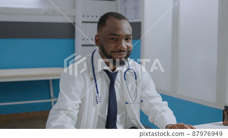Portrait of african american therapist doctor analyzing sickness diagnostic document typing medical expertise. Specialist physician man working at healthcare treatment in hospital office Portrait of african american therapist doctor analyzing sickness diagnostic document typing medical expertise. Specialist physician man working at healthcare treatment in hospital office 87976949