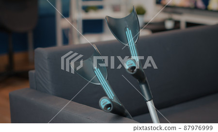 Empty couch with crutches on it for person with physical disability or injury. Walking sticks giving aid and support for transportation and mobility on sofa. Medical care equipment. 87976999