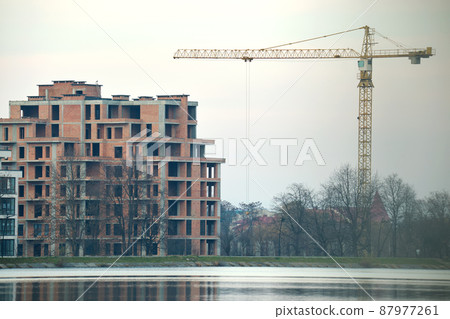 Tower crane at high residential apartment buildings construction site. Real estate development Tower crane at high residential apartment buildings construction site. Real estate development 87977261