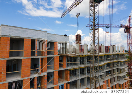 Tower crane at high concrete residential building under construction. Real estate development concept. Tower crane at high concrete residential building under construction. Real estate development concept. 87977264