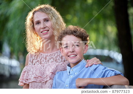 Pretty young mother with her son enjoying time together in summer park. Happy family leasure activity concept 87977323