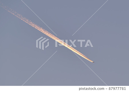 Distant passenger jet plane flying on high altitude on clear blue sky leaving white smoke trace of contrail behind. Air transportation concept 87977781
