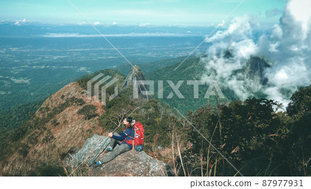 Hiker with backpacks reaches the summit of mountain peak. Hiker with backpacks reaches the summit of mountain peak. 87977931