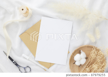 Blank greeting card invitation Mockup 5x7 on envelope with dry flowers and ribbon on white fabric background, flat lay, mockup Blank greeting card invitation Mockup 5x7 on envelope with dry flowers and ribbon on white fabric background, flat lay, mockup 87979255