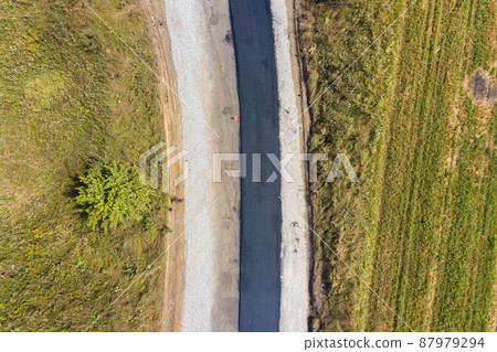 Aerial view of new road construction with newly layed black asphalt lane. 87979294
