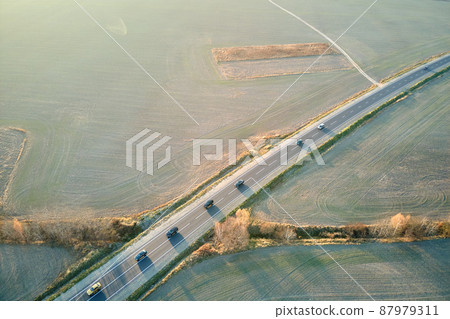 Aerial view of intercity road with fast driving cars at sunset. Top view from drone of highway traffic in evening Aerial view of intercity road with fast driving cars at sunset. Top view from drone of highway traffic in evening 87979311