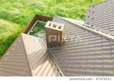 Aerial view of house roof structure covered with brown metal tile sheets. 87979312