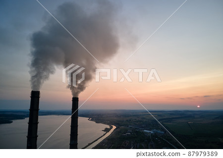 Aerial view of coal power plant high pipes with black smoke moving upwards polluting atmosphere at sunset. Production of electrical energy with fossil fuel concept Aerial view of coal power plant high pipes with black smoke moving upwards polluting atmosphere at sunset. Production of electrical energy with fossil fuel concept 87979389