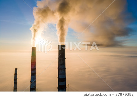 Aerial view of coal power plant high pipes with black smoke moving up polluting atmosphere at sunset. Aerial view of coal power plant high pipes with black smoke moving up polluting atmosphere at sunset. 87979392