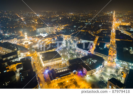 Aerial view of bright illuminated streets and buildings in Ukrainian Ivano-Frankivsk city center at night. 87979418