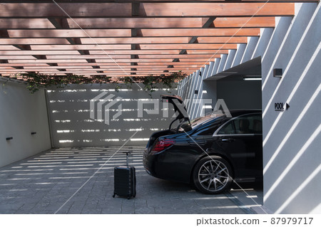 A photo of a suitcase standing next to a car in a luxury garage. Selective focus  87979717