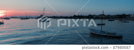 Sunrise on the seashore. In the silhouette of the ships in the harbor. Selective focus Sunrise on the seashore. In the silhouette of the ships in the harbor. Selective focus 87980087