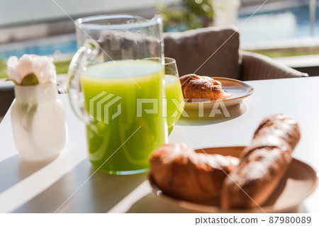 Healthy breakfast served on wooden table in space with window and natural light with yogurt and green smoothie in glasses and glass jar, chopped bread on black plate . Healthy breakfast served on wooden table in space with window and natural light with yogurt and green smoothie in glasses and glass jar, chopped bread on black plate . 87980089
