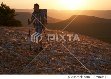 Hike mountain man hiking travel with backpack and trekking poles walking at adventure and sunset. High quality photo. 87980519