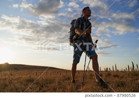 Hike mountain man hiking travel with backpack and trekking poles walking at adventure and sunset. High quality photo. 87980526