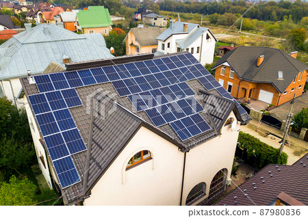 Aerial view of a private house with solar photovoltaic panels for producing clean electricity on roof. Autonomous home concept. Aerial view of a private house with solar photovoltaic panels for producing clean electricity on roof. Autonomous home concept. 87980836