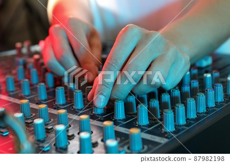 The musician adjusts the sound on audio mixer 87982198