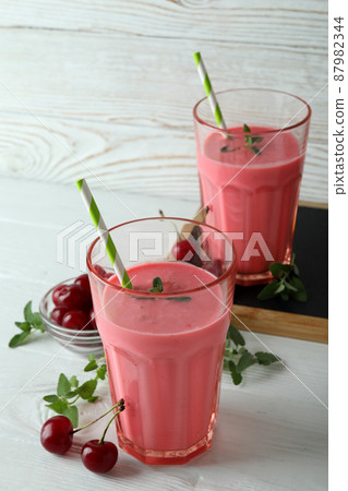 Glasses of cherry smoothie and ingredients on white wooden table Glasses of cherry smoothie and ingredients on white wooden table 87982344