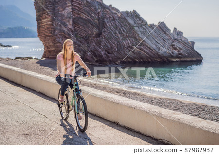 Woman tourist on a bicycle explores Budva in Montenegro. Cycling in Montenegro concept 87982932
