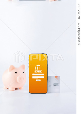 Mobile banking. Smartphone with internet online bank application. Piggy bank with debit card on white background. Save money business concept. 87983028