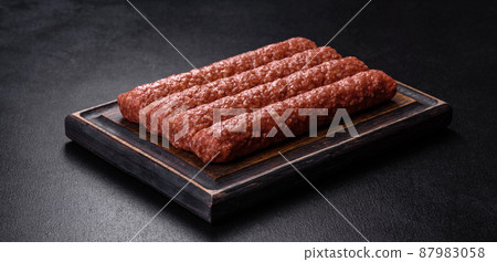 Fresh raw mince for grilled kebab with spices and herbs on a dark concrete background 87983058
