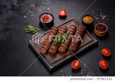Grilled kebab with spices and herbs on a dark concrete background Grilled kebab with spices and herbs on a dark concrete background 87983101