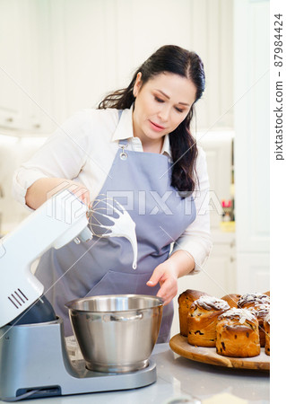 a woman cook prepares icing, fondant or marshmallow to decorate easter cakes. 87984424