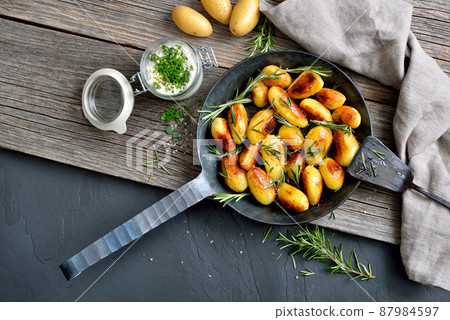 Golden brown fried potatoes with rosemary and herb curd Golden brown fried potatoes with rosemary and herb curd 87984597