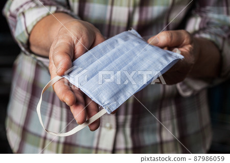 Female caucasian person holding homemade DIY fabric face mask in hands 87986059