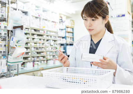 A woman working in a dispensing pharmacy 87986280